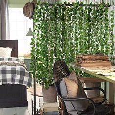 a bedroom with a bed, desk and chair next to a green plant covered wall