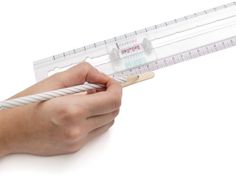 a person is holding a ruler and measuring it with both hands on the white surface