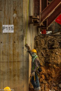 a man is climbing up the side of a building with a yellow helmet and safety harness