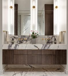 a bathroom with marble counter top and double sinks under three large mirrors on the wall