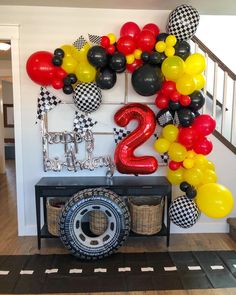 balloons are hanging on the wall in front of a table with a tire and sign