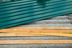 several pieces of wood sitting on top of each other in front of a green roof