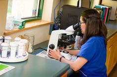 a girl looking through a microscope in a lab