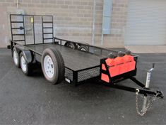 a trailer with a red bag on the back and two wheels parked in front of a brick wall