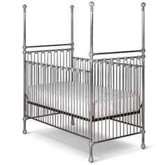 the crib is made from metal and has a white blanket on top of it