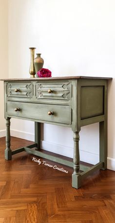 a green table with two drawers and a vase on top