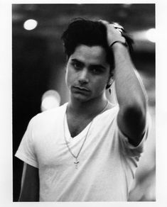 black and white photograph of a young man holding his hair in one hand while looking at the camera