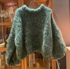 a green sweater hanging on a book shelf