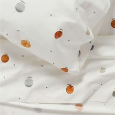 an unmade bed with white sheets and planets on it