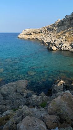 the water is crystal blue and clear at this rocky shore line, with rocks on both sides