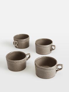 four cups with handles are shown on a white surface