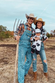 Man and woman dressed as farmers and holding a child dressed as a cow Halloween Family Of Three Costumes, Couple With Newborn Halloween Costumes, Cute Family Of Three Halloween Costumes, Matching Halloween Costumes For Family Of 3, Steve Irwin Family Costume, Couple And Newborn Halloween Costumes, Family Of Three Costumes Halloween, Scarecrow Family Halloween Costumes, Farmers Family Costume