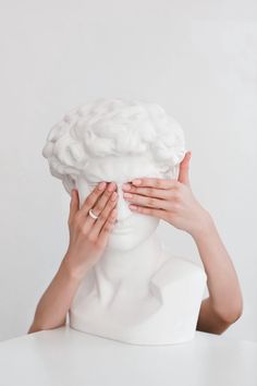 a woman covering her face with hands while sitting in front of a white busturine