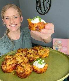 a woman holding up some food on a green plate