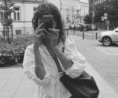 a woman taking a photo with her cell phone on the sidewalk in front of some buildings