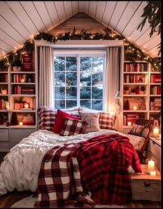 a bedroom decorated for christmas with plaid blankets and candles on the windowsill, bookshelves in the background