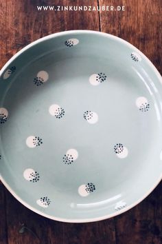 a bowl with polka dots on it sitting on top of a wooden table next to a spoon