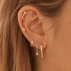 a close up of a person's ear wearing gold earrings with diamond details on them