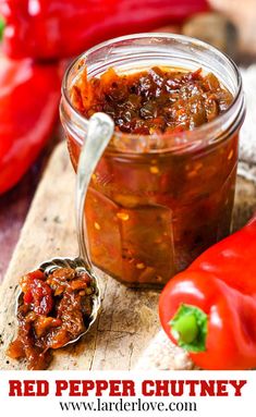 red pepper chutney in a glass jar with spoon and peppers on the side