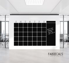 a large black and white calendar on the wall in an empty office space with glass doors