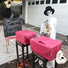 a skeleton dressed up with a hat and holding a knife next to two pink boxes