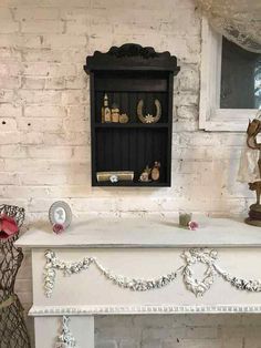 a white fireplace with an ornate mantle and shelf above it in a room that has exposed brick walls