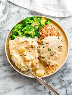 a bowl filled with chicken, mashed potatoes and broccoli covered in gravy