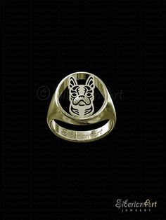 a gold ring with a dog's face on the front and bottom, in black background