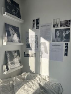 a bed with white sheets and pictures hanging on the wall above it in a bedroom