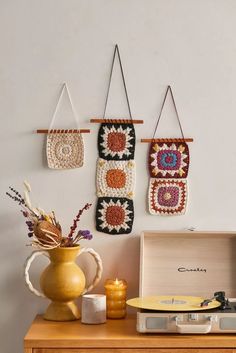 three crocheted wall hangings hang above a record player