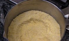 a metal bowl filled with flour on top of a stove