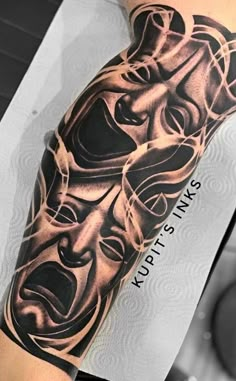 a man's arm with tattoos on it and an image of two masks in the middle