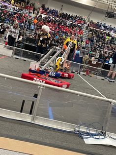 a man riding on the back of a red race car in front of a crowd