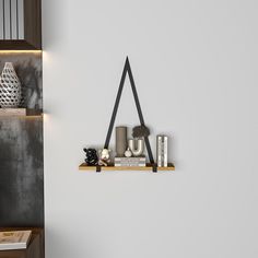 a white wall with some books and candles on it, along with a black triangle hanging from the wall