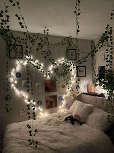 an unmade bed with plants growing on the headboard and lights hanging from the ceiling