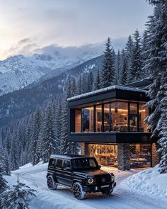 a black suv parked in front of a house on a snow covered road with mountains in the background