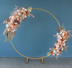 a circular gold frame with flowers and foliage on it, against a blue wall background