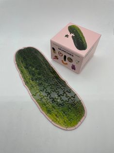 a cucumber shaped puzzle sitting on top of a white table next to a box