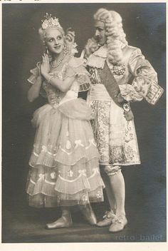 an old black and white photo of two people dressed in fancy clothing, one wearing a tiara