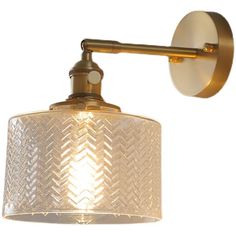 an old fashioned wall light with a white shade on the side and a gold arm