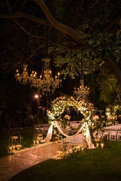 an outdoor wedding setup with chandeliers and candles