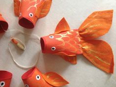 four orange fish made out of toilet paper with eyes and tails, sitting on a white surface