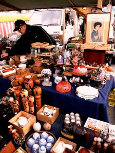 a table with many items on it and a man in black jacket looking at them