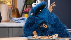 a cookie monster sitting at a table with cookies in front of it