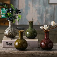 three different vases sitting on top of a box with flowers in them and the words real