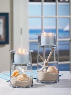 two candles sitting on top of a table with seashells and starfish in them