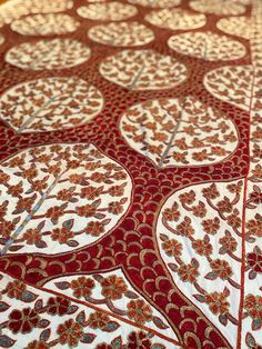 an intricately designed table cloth with red and white designs on it's surface