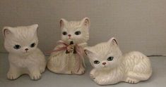 three white kitten figurines sitting next to each other