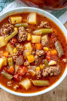 a white bowl filled with meat and vegetable soup on top of a wooden cutting board