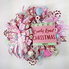 a pink wreath with candy land christmas decorations on the front and side, along with a sign that reads candy land christmas it's the sweetest season